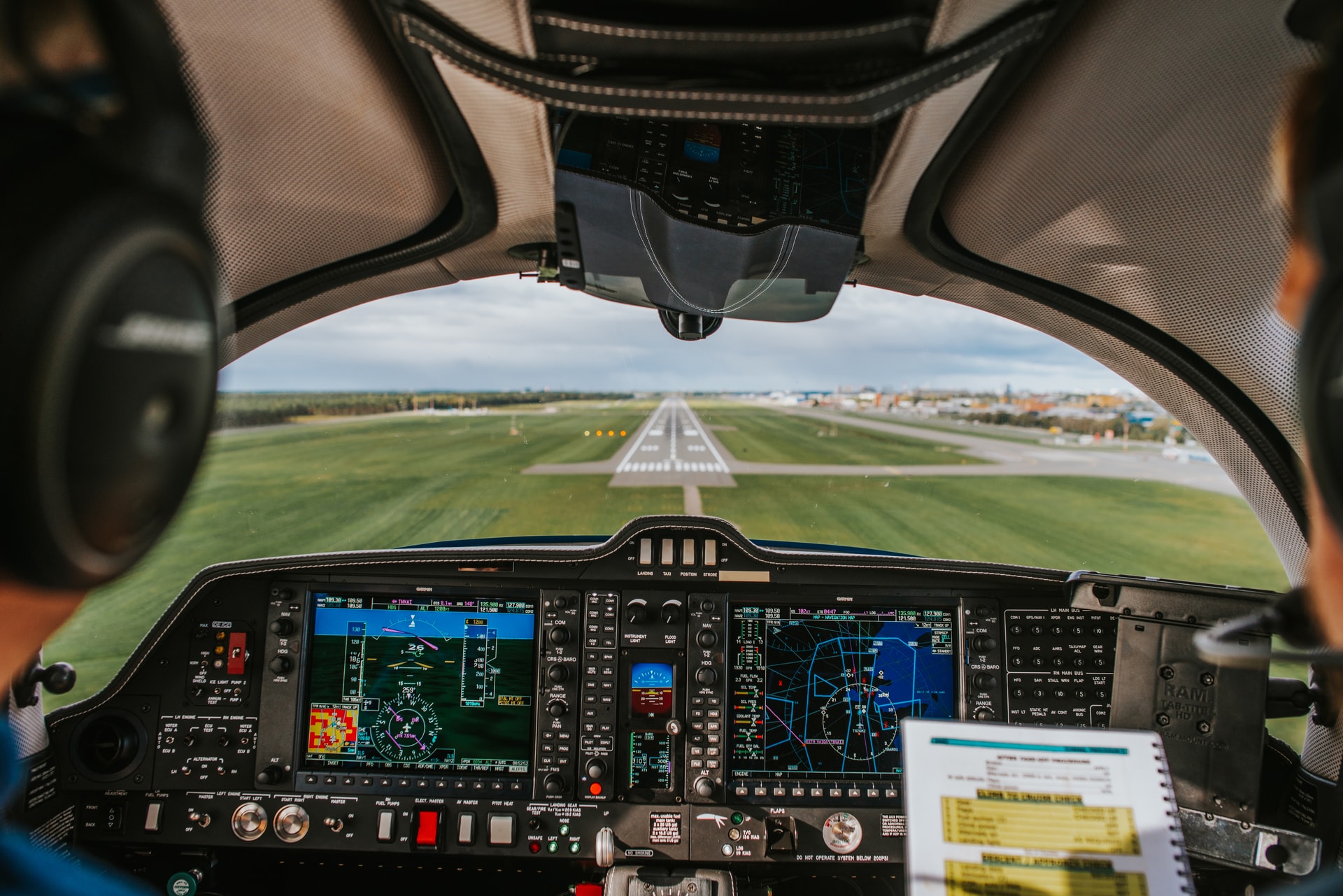 Two pilots approaching a runway and checking guidelines on a handbook.