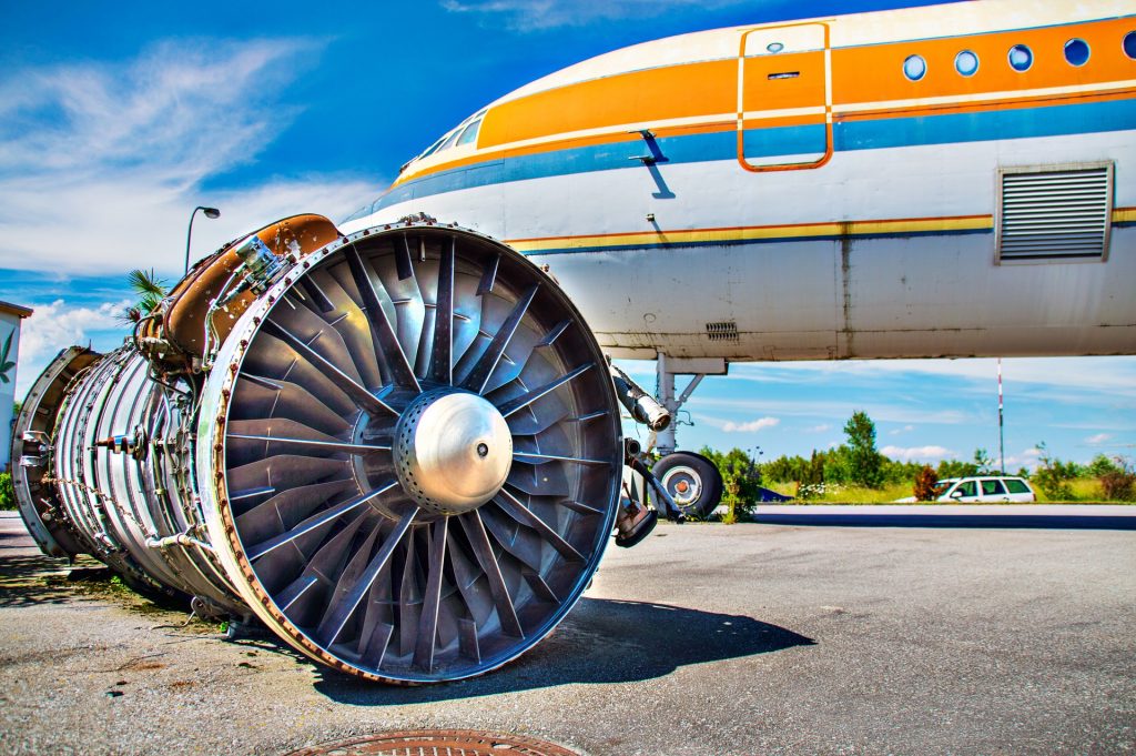 An airplane turbine placed on the ground next to an aircraft. 