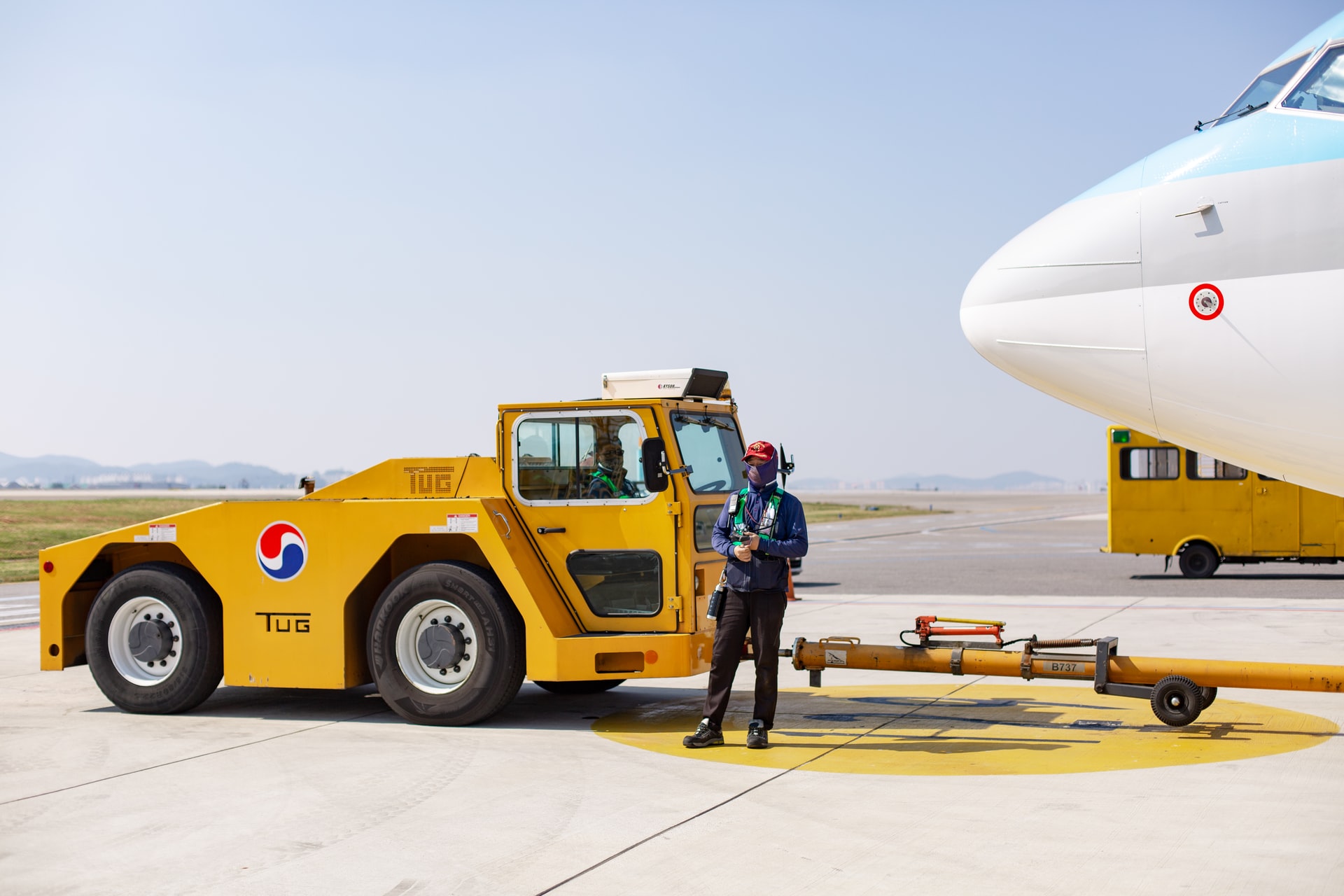 A ground staff member standing by the aircraft which is ready to be pushed to the runway.
