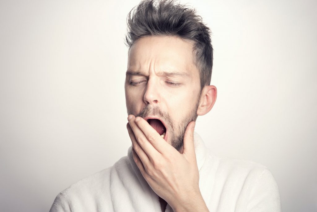 A person experiencing fatigue: yawning and covering their mouth with their hand.