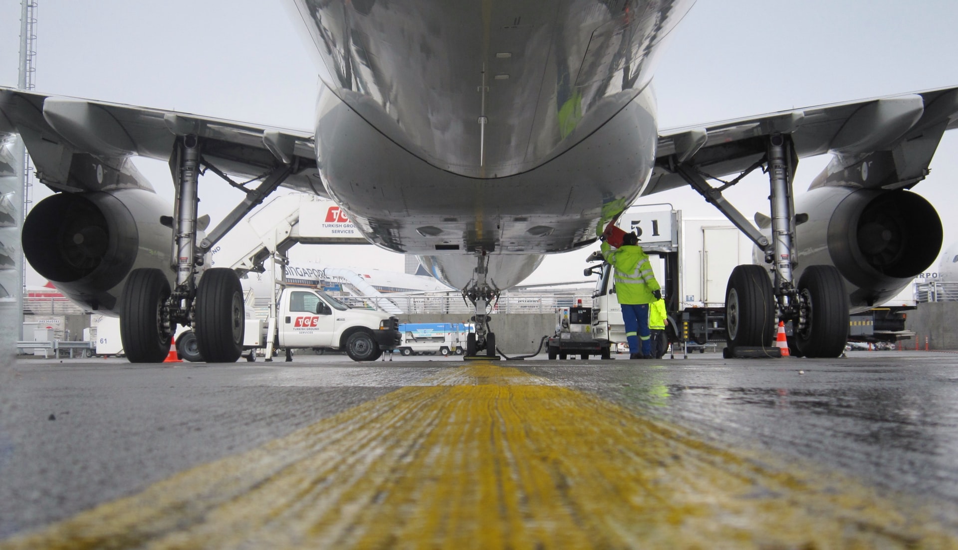 Two engineers working under an aircraft's wing.