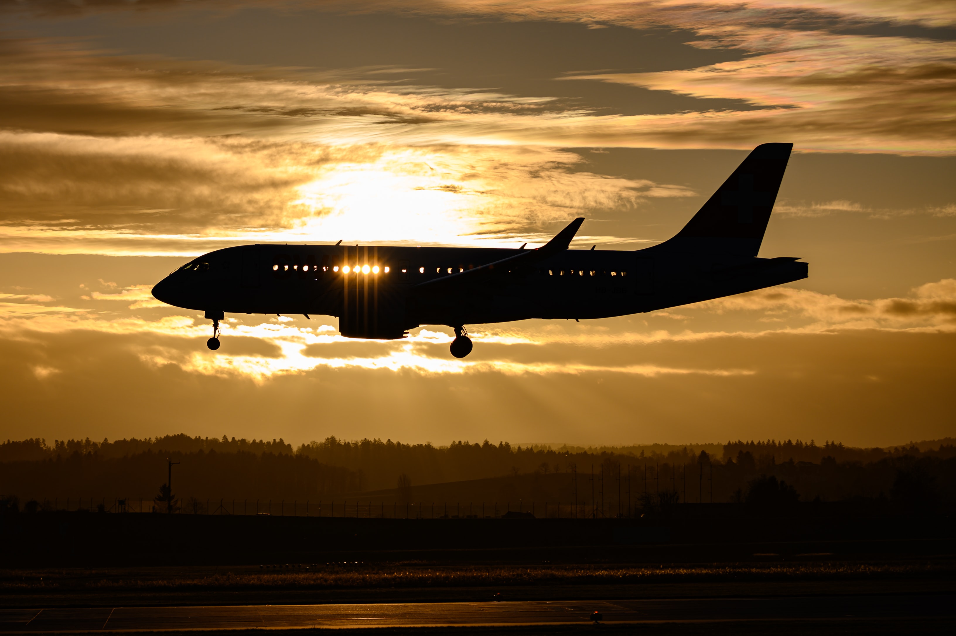 A commercial aircraft flying in front of the setting sun.