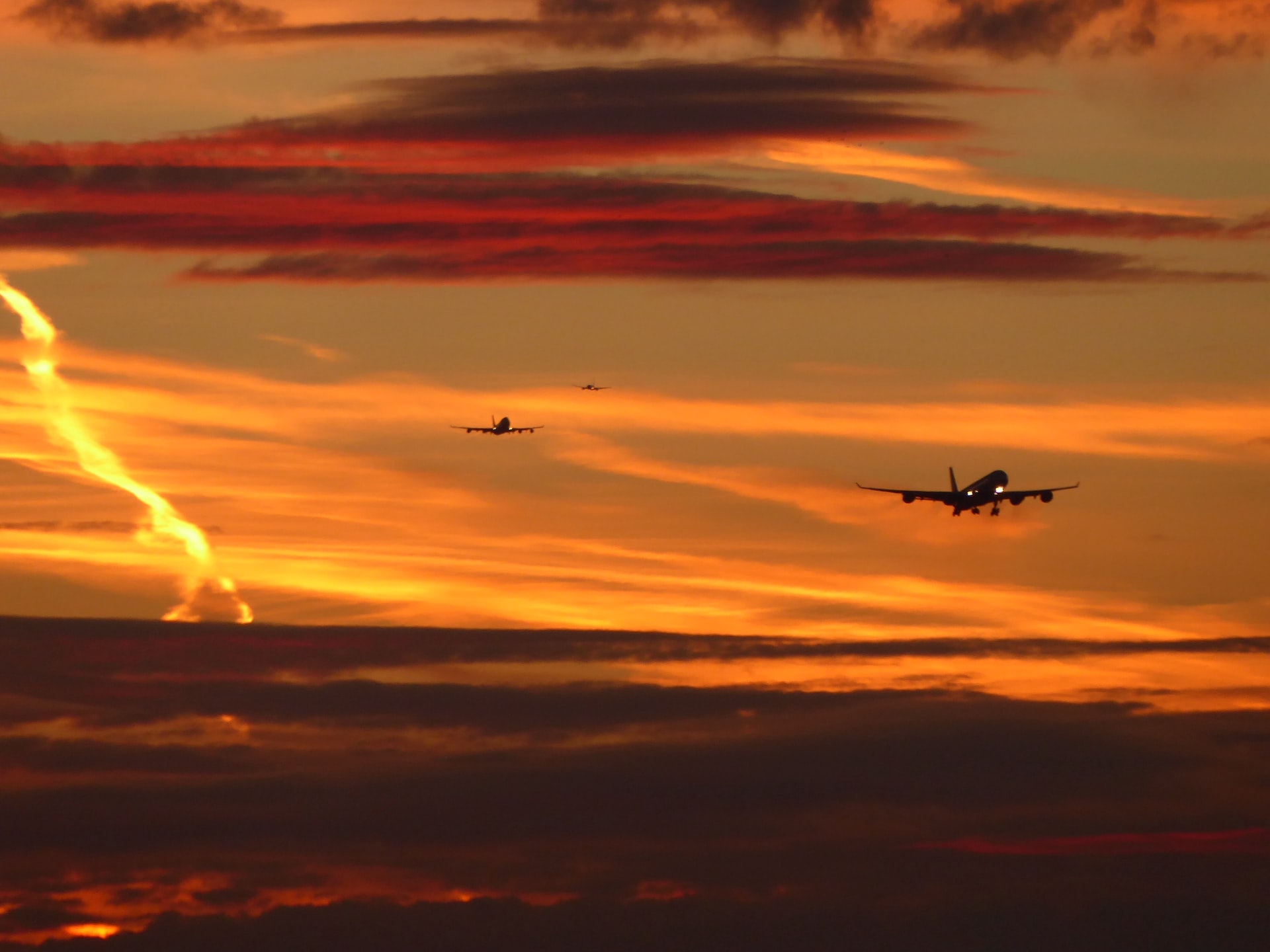 Three airplane landing from a sunny evening sky.