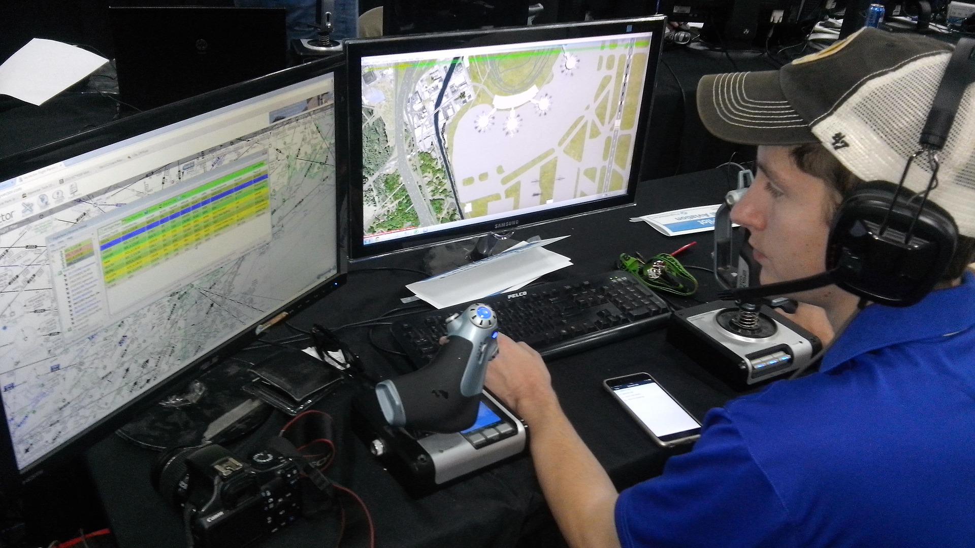 An air traffic controller at work in front of two screens and other tools. 