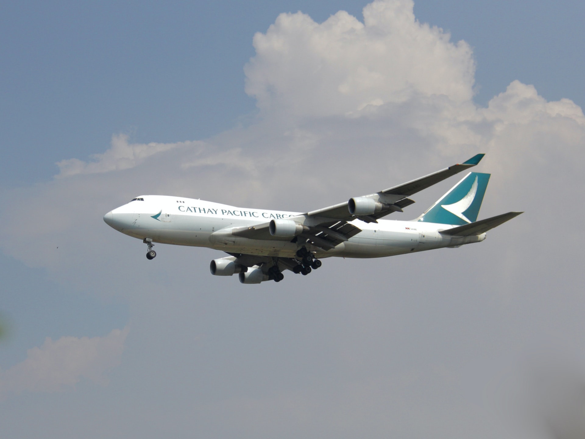 Cathay Pacific aircraft in flight over a cloudy sky.