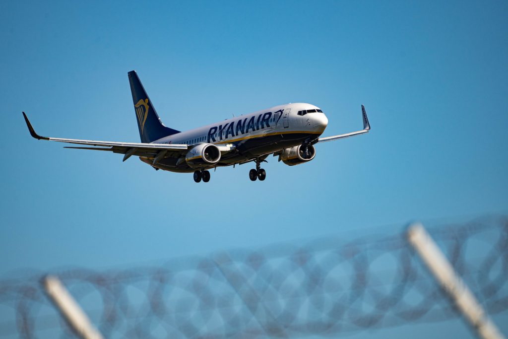 Ryanair aircraft landing at an airport behind the fence.