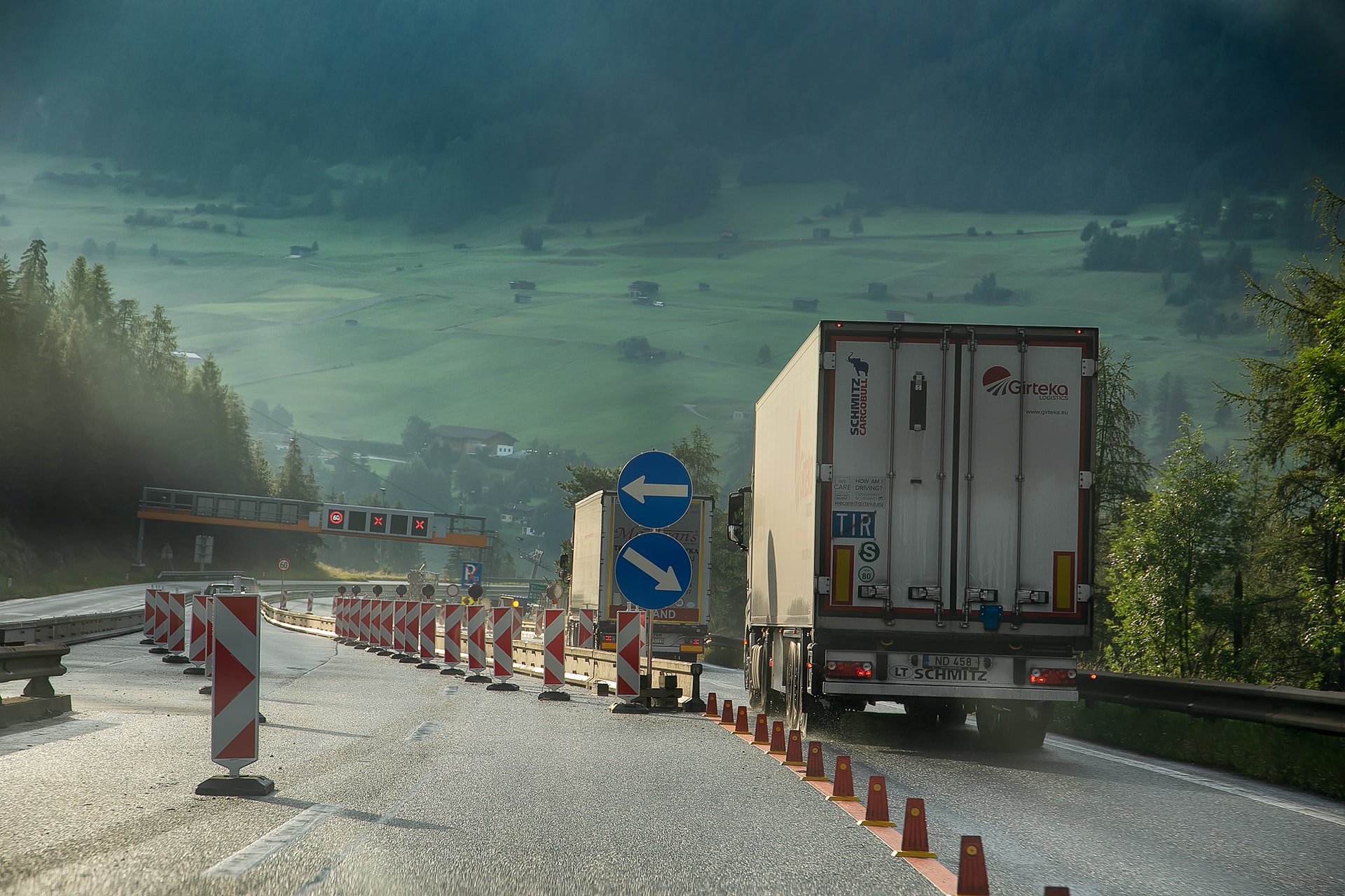 Cargo trucks driving down a road leading down the mountain.