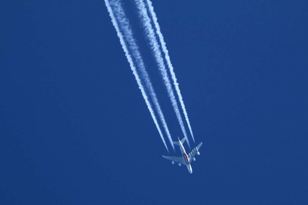 An Emirates aircraft flying with a contrail.