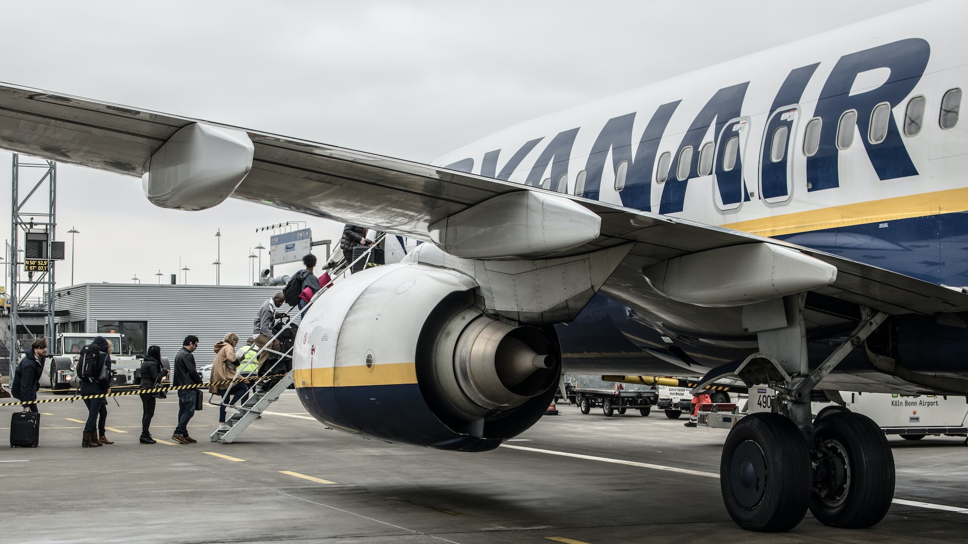 Ryanair passengers boarding the aircraft on a cloudy day.