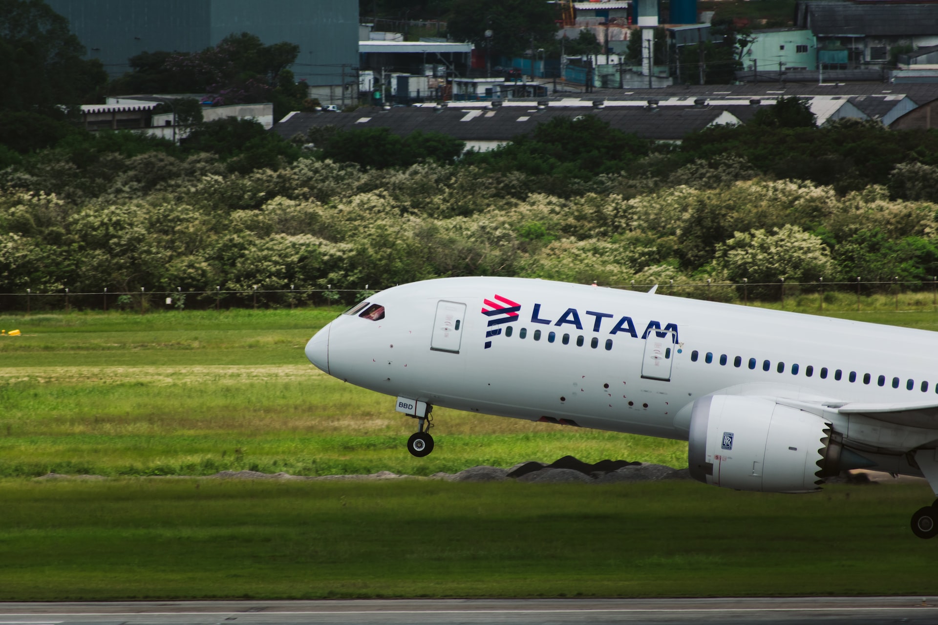 A white LATAM commercial aircraft landing on a runway.