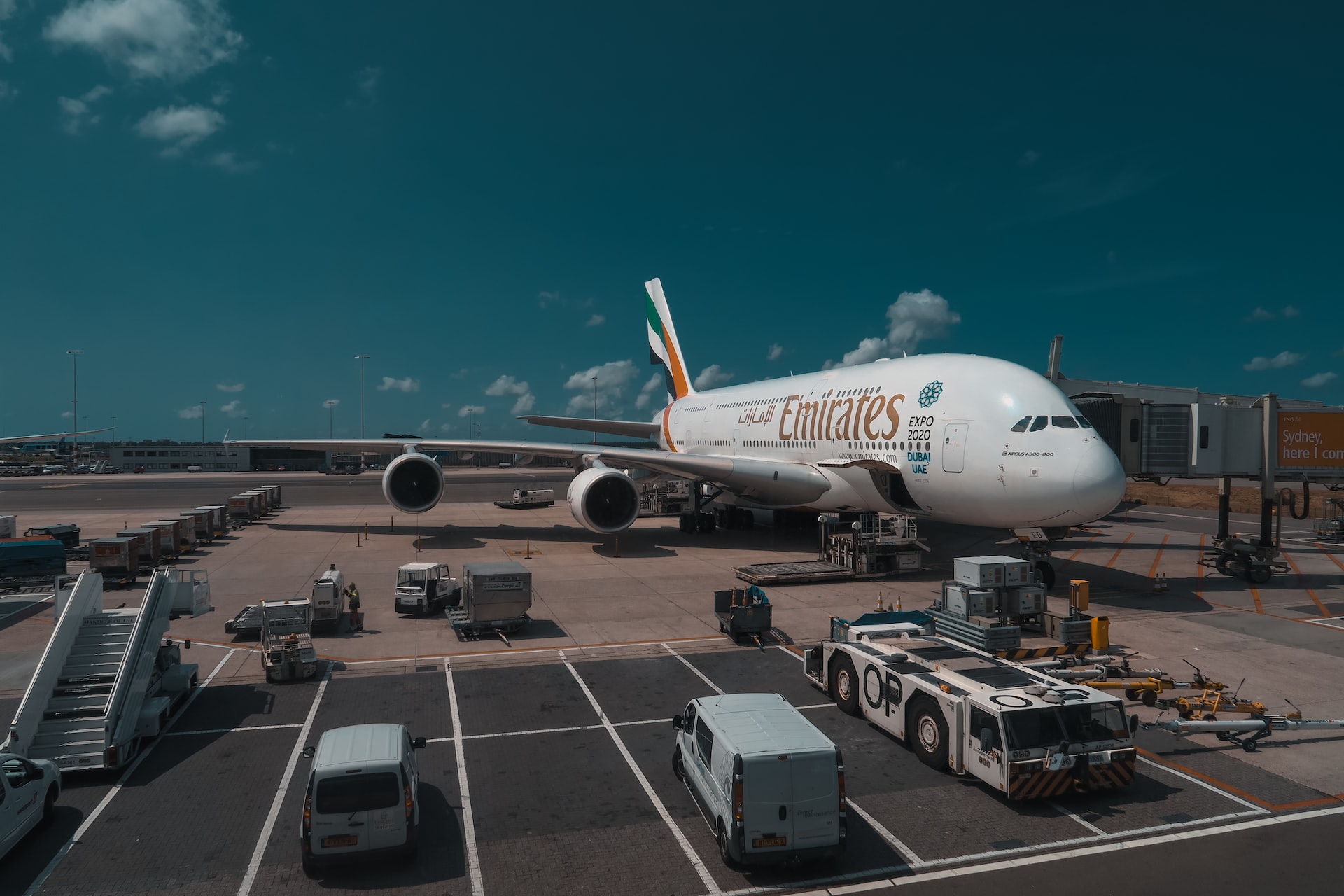 An Emirates airlines jumbo jet parked at a jetway.