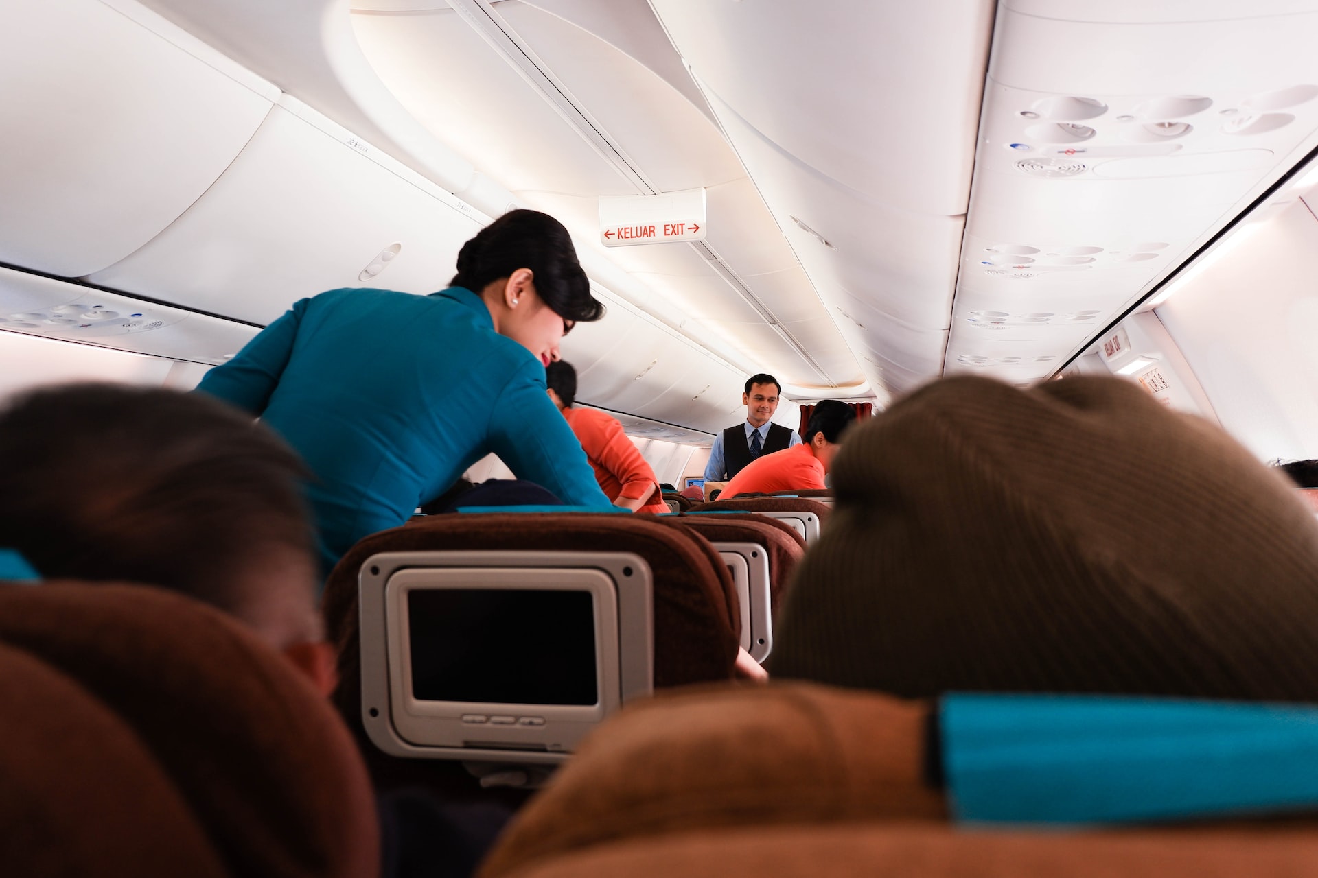 Cabin crew helping the passengers onboard an aircraft before the flight.