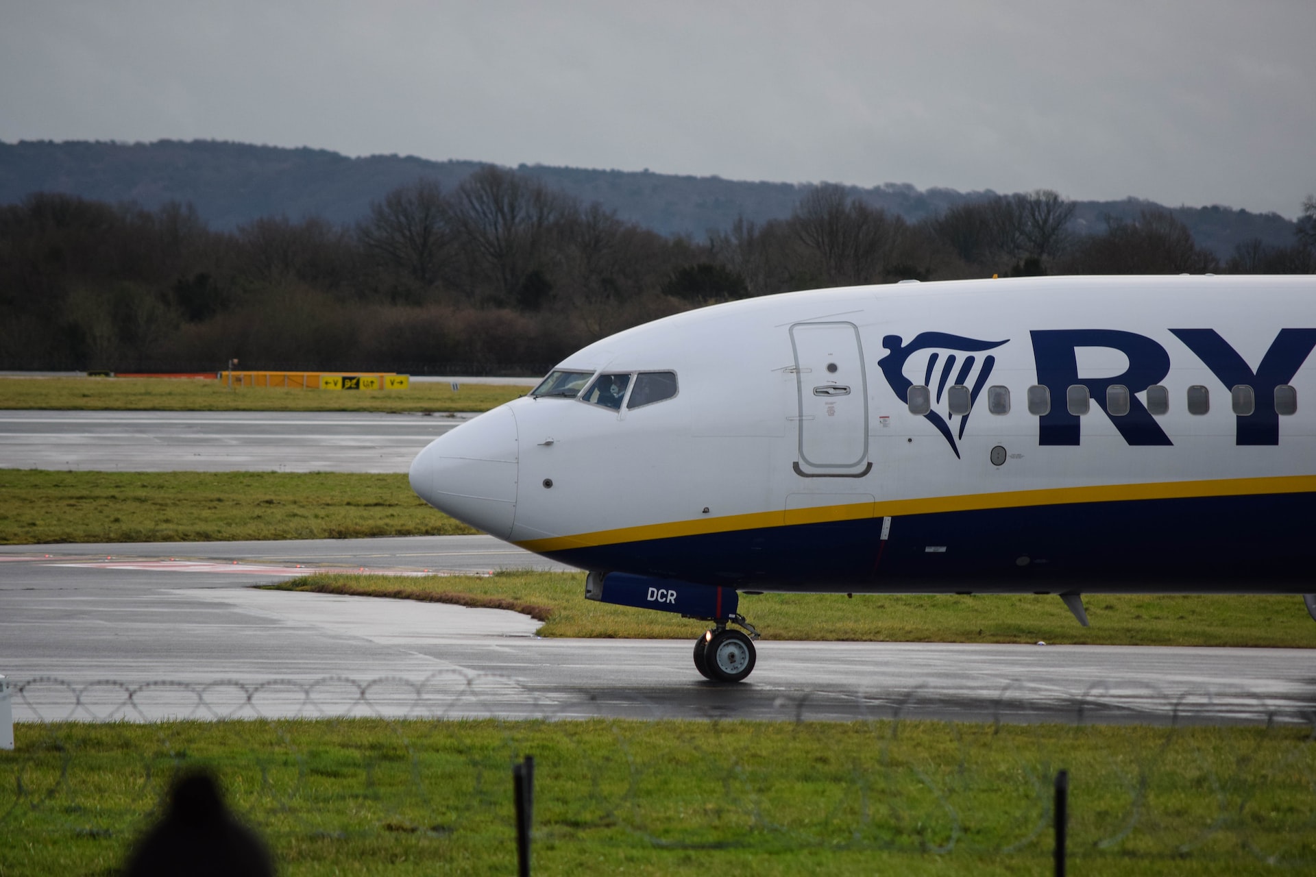 Ryanair aircraft taxiing to the runway on a rainy day.