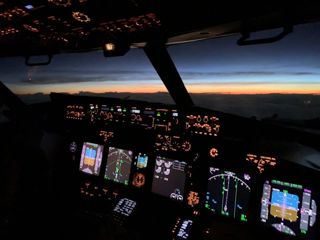 Airplane cockpit at night with illuminated instrument screens, including GPWS.