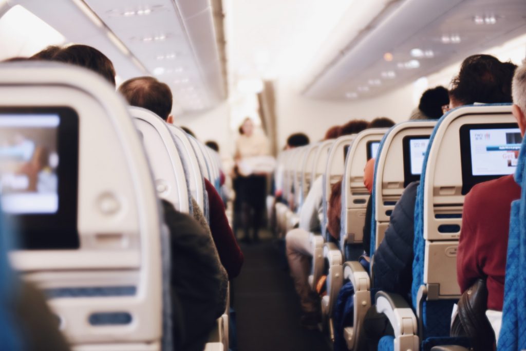 Cabin crew giving airplane safety instructions to the passengers seated in the cabin.