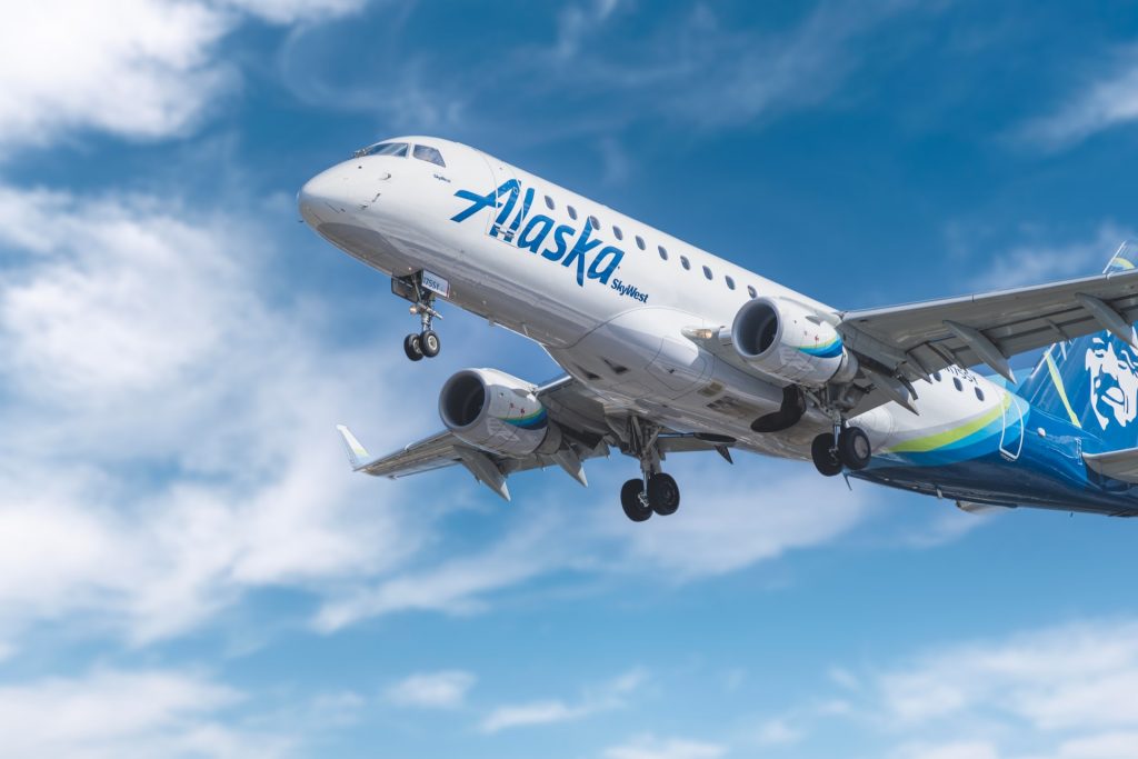 Environmentally friendly Alaska Airlines aircraft taking off on a clear day.