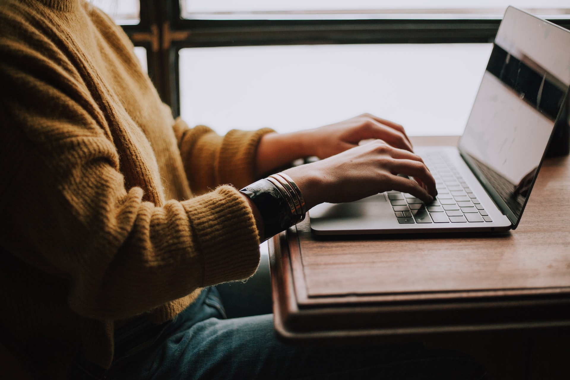 A person typing a pilot cover letter on his laptop.