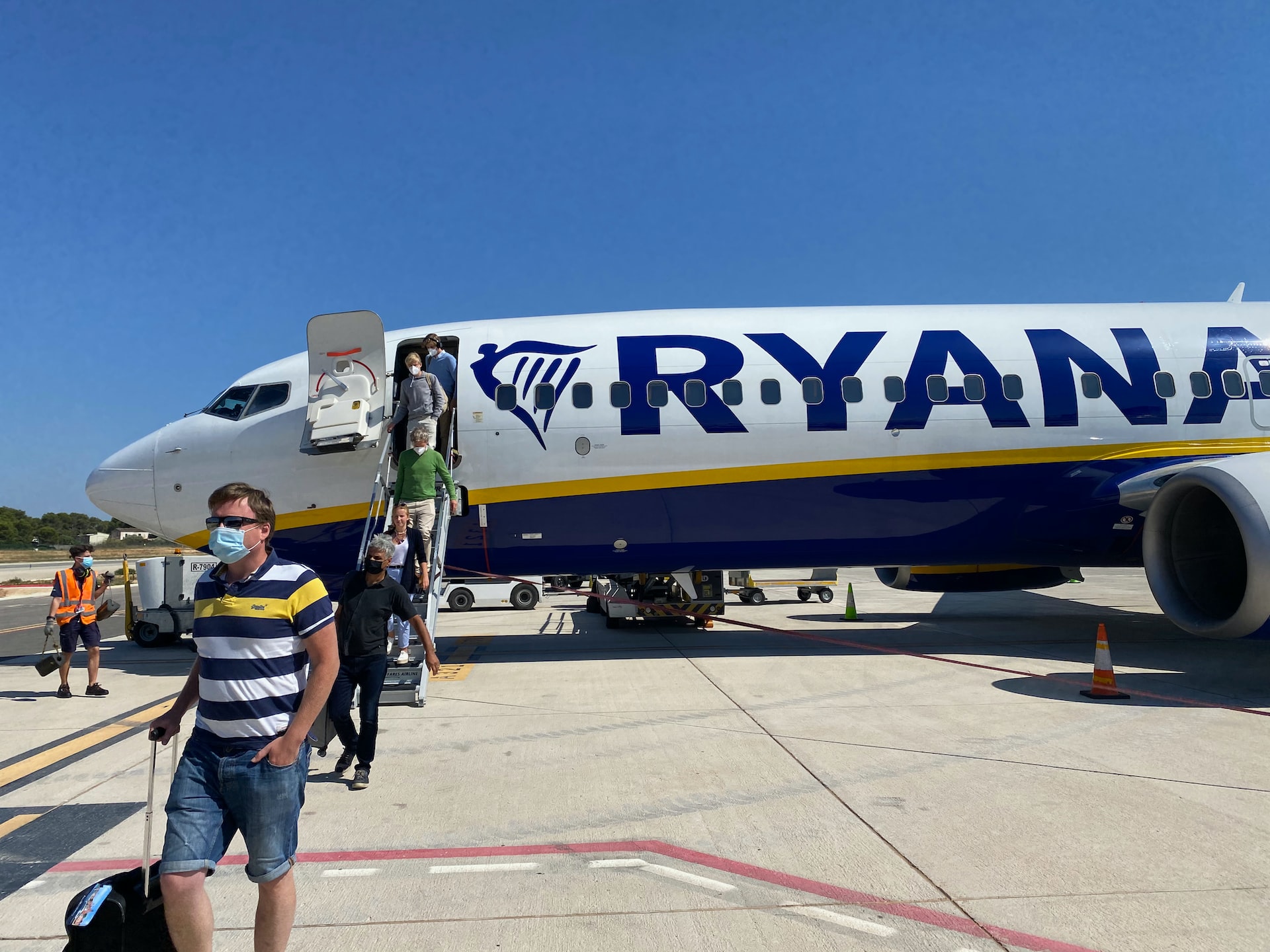 Passengers disembarking a plane with Ryanair hand luggage.