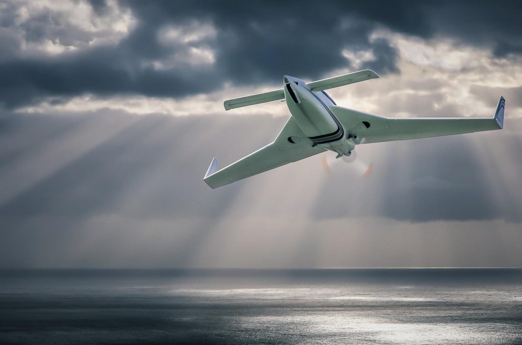 Plane with canards flying over a bay.